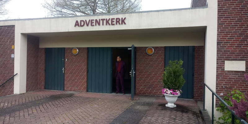 De hoofdingang met groene deuren en het woord Adventkerk boven de deur